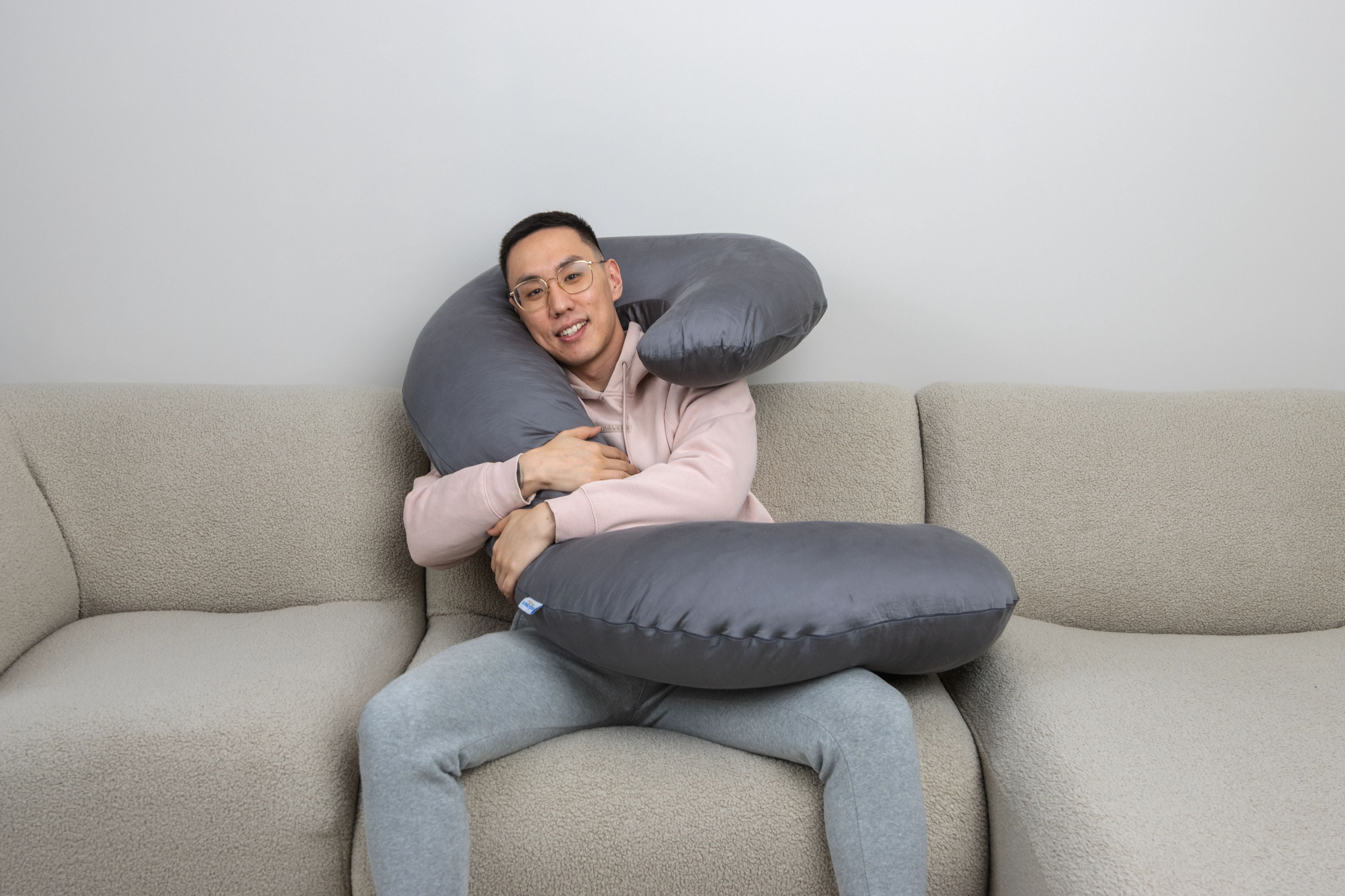Ed, co-founder of Comfybud, relaxing with the C-shaped body pillow designed for side sleepers, comfort, and full-body support