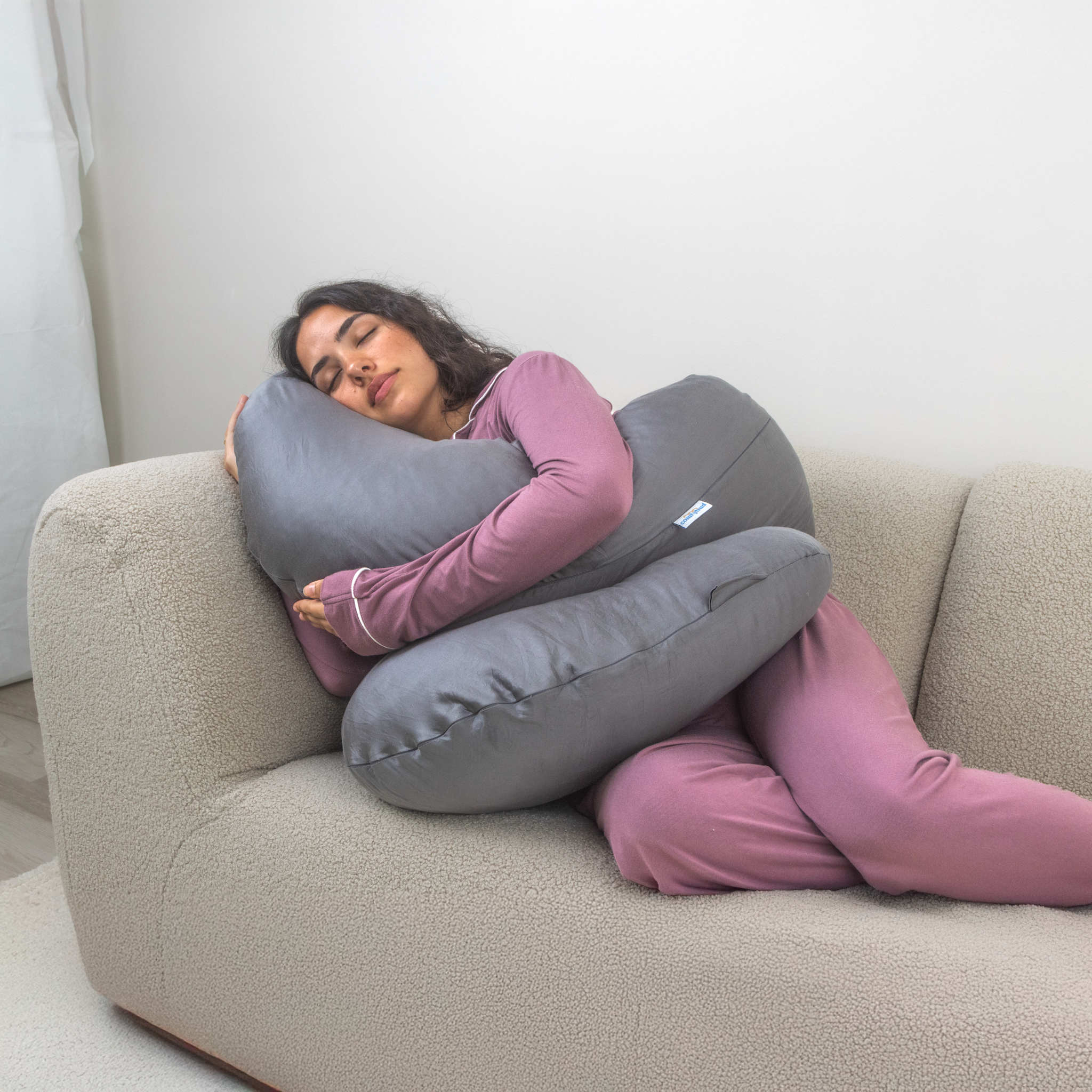 Woman peacefully relaxing with Comfybud body and pregnancy pillow, showcasing versatile comfort for sleep, lounging, and support