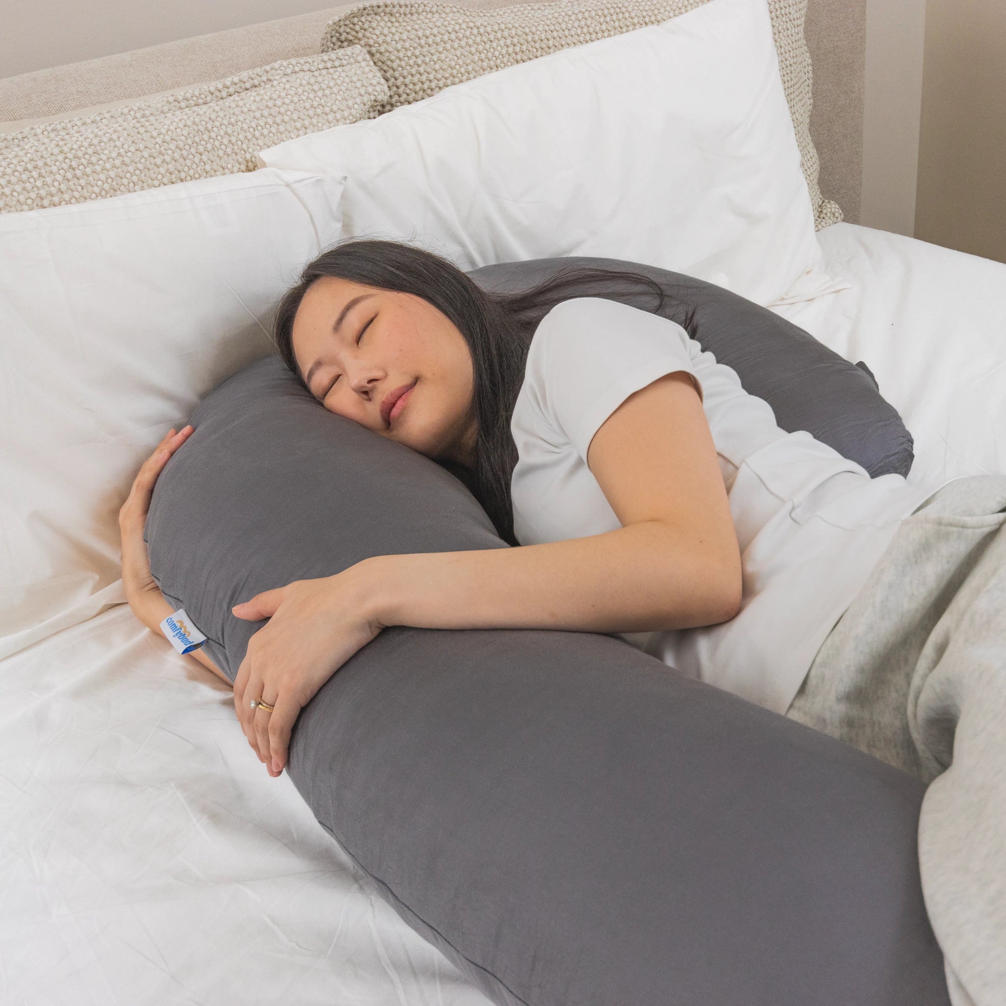 Woman peacefully sleeping with Comfybud C-shaped body and pregnancy pillow, ideal for maternity support, neck pain, and cooling comfort