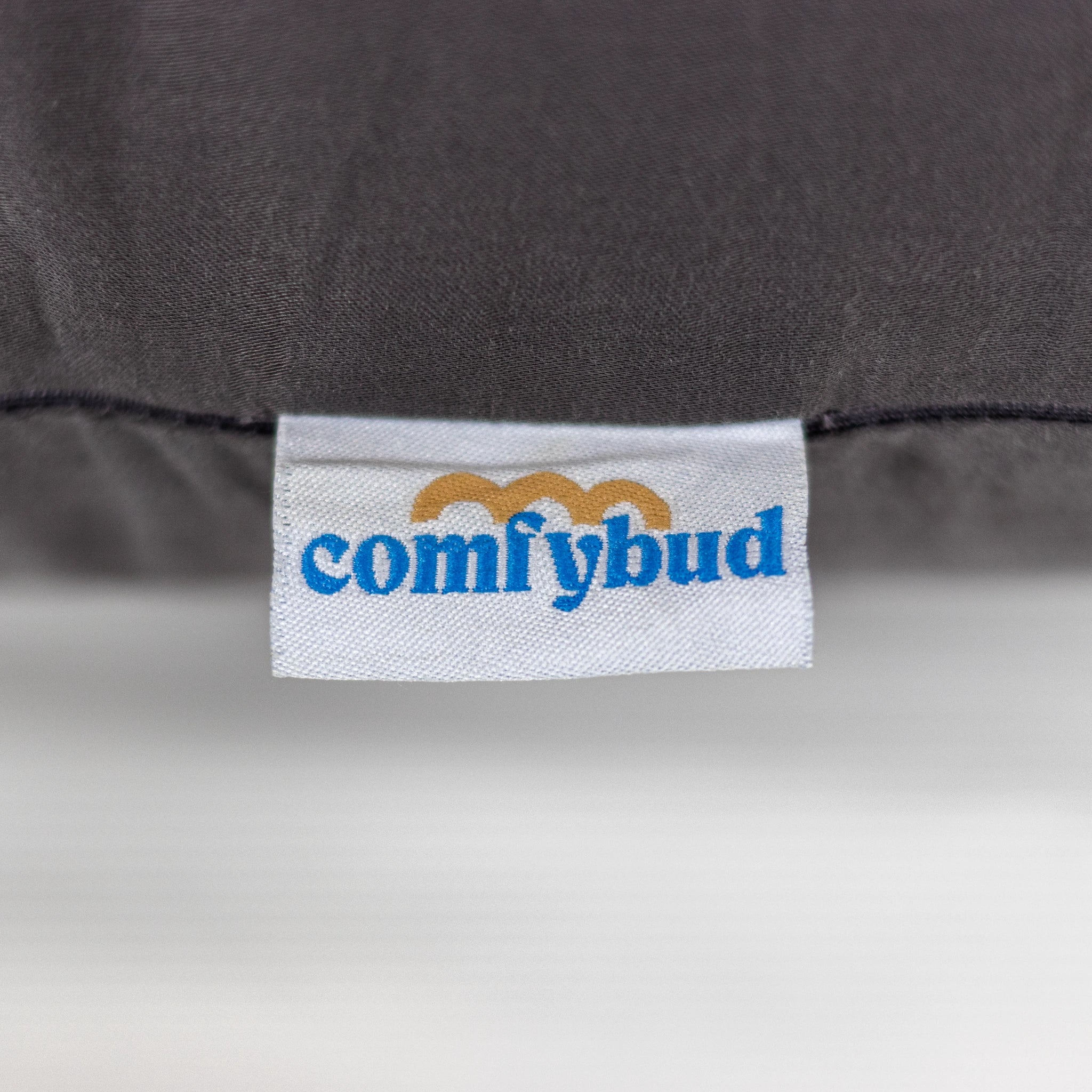 Close-up of Comfybud logo tag on grey C-shaped pregnancy and body pillow, showcasing premium quality and thoughtful design