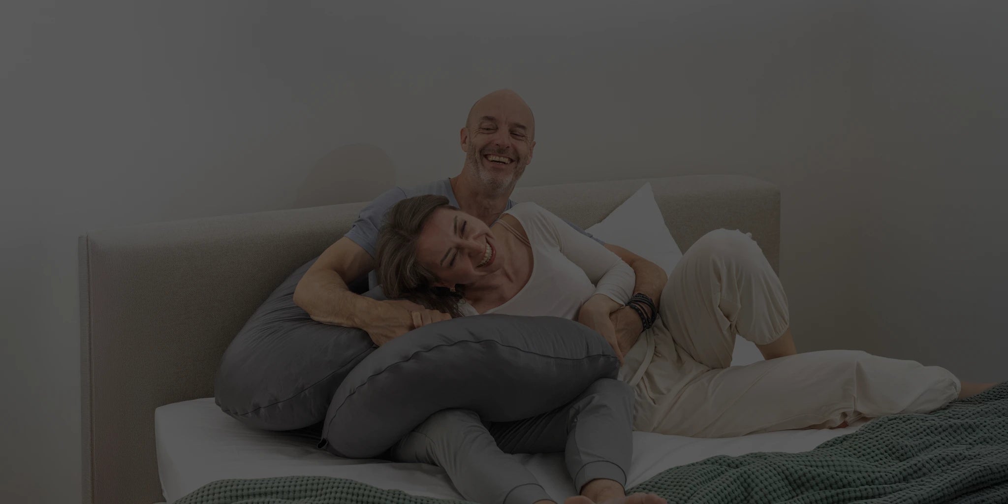 Laughing couple relaxing with Comfybud body pillow, capturing warmth, connection, and approachability for Comfybud customer support